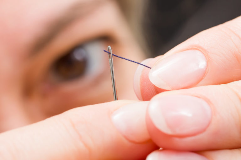 Macro of woman's fingers threading a needle